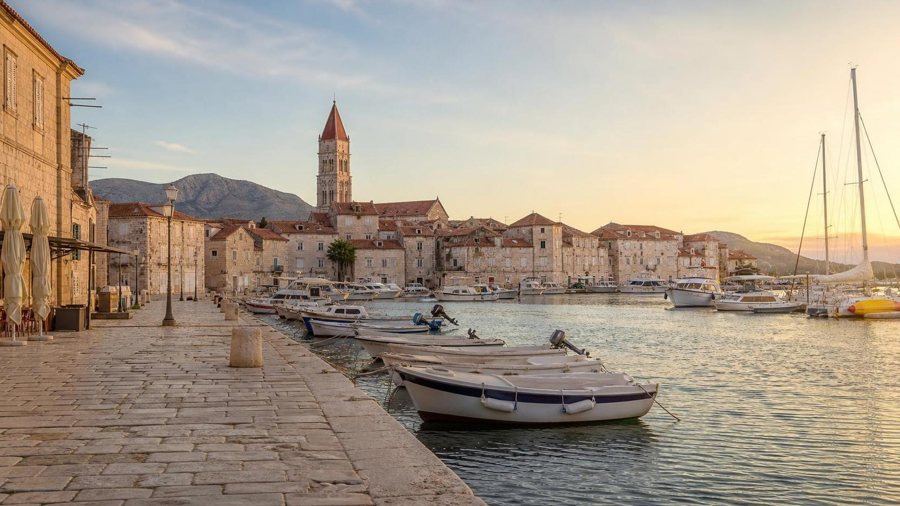 AI-generierte Illustration einer steinernen Altstadt am kroatischen Hafen mit Booten und Kirchturm